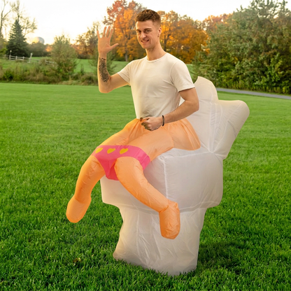 Three quarter view of adult in inflatable toilet costume waving, white toilet with faux legs in pink briefs