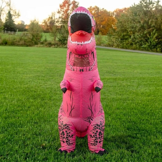 Front view of inflatable pink T-Rex costume with open toothy jaw and small arms on green grass