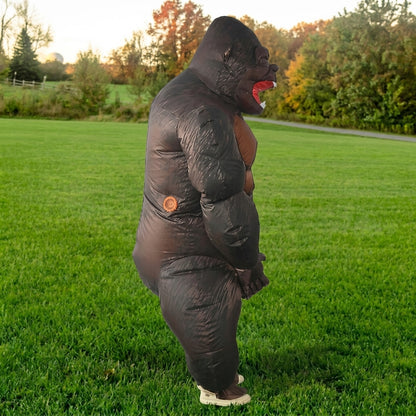 Side profile of dark inflatable gorilla costume with red mouth, hunched pose on a lawn